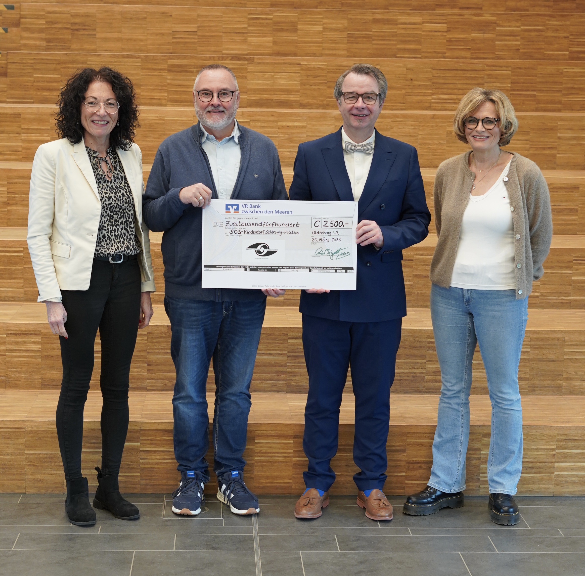 Schuldirektor Herr Bigott hält einen großen Check in der Hand, umrahmt von der Vertretung des SOS Kinderdorfes und der Unterstufenleiterin Frau Westenhoff