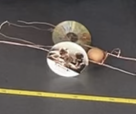 Eiertransporter bestehend aus zwei CDs verbunden mit Kupferdrähten, in deren Mitte ein Ei transportiert wird.